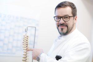 Dr. Robert Morrison zeigt auf ein Modell einer Wirbelsäule