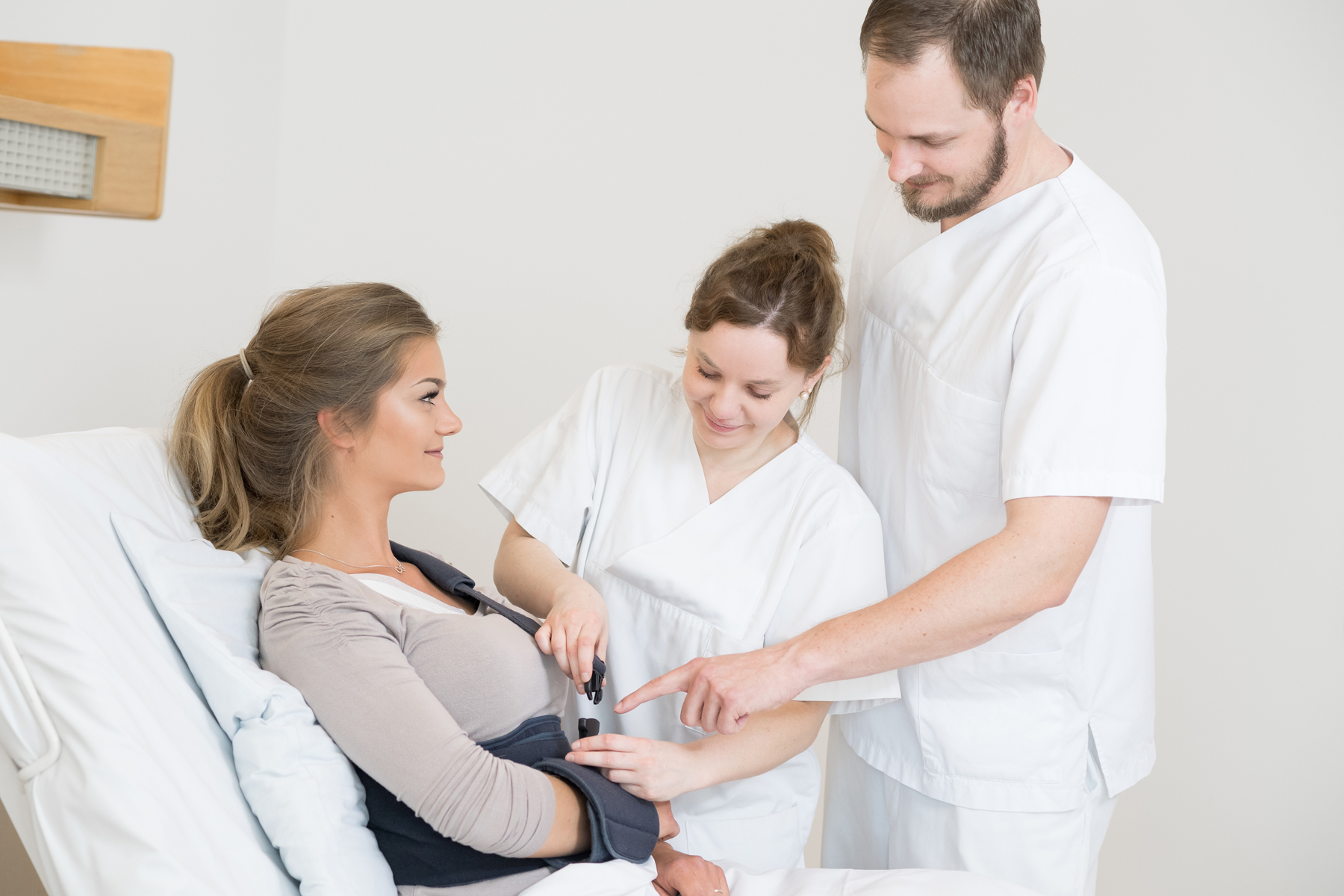 Zwei Pflegekräfte des Klinikums Ingolstadt helfen einer Patientin mit ihrer Armschlaufe