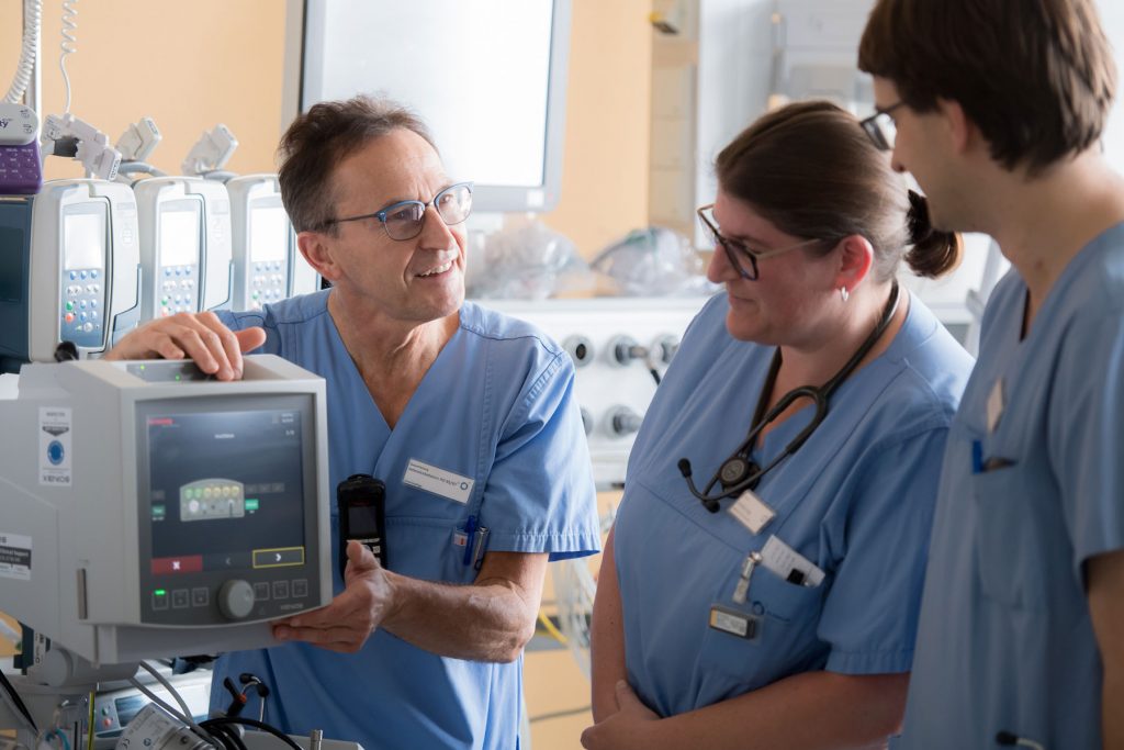 Der leitende Intensivpfleger erklärt zwei Kollegen die Bedienung eines Überwachungsgerätes auf der Intensivstation des Klinikums Ingolstadt