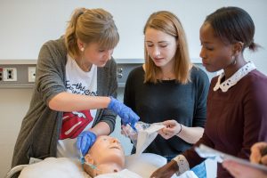 Drei Auszubildende des Klinikums Ingolstadt üben an einer Puppe das Legen eines Venenzugangs